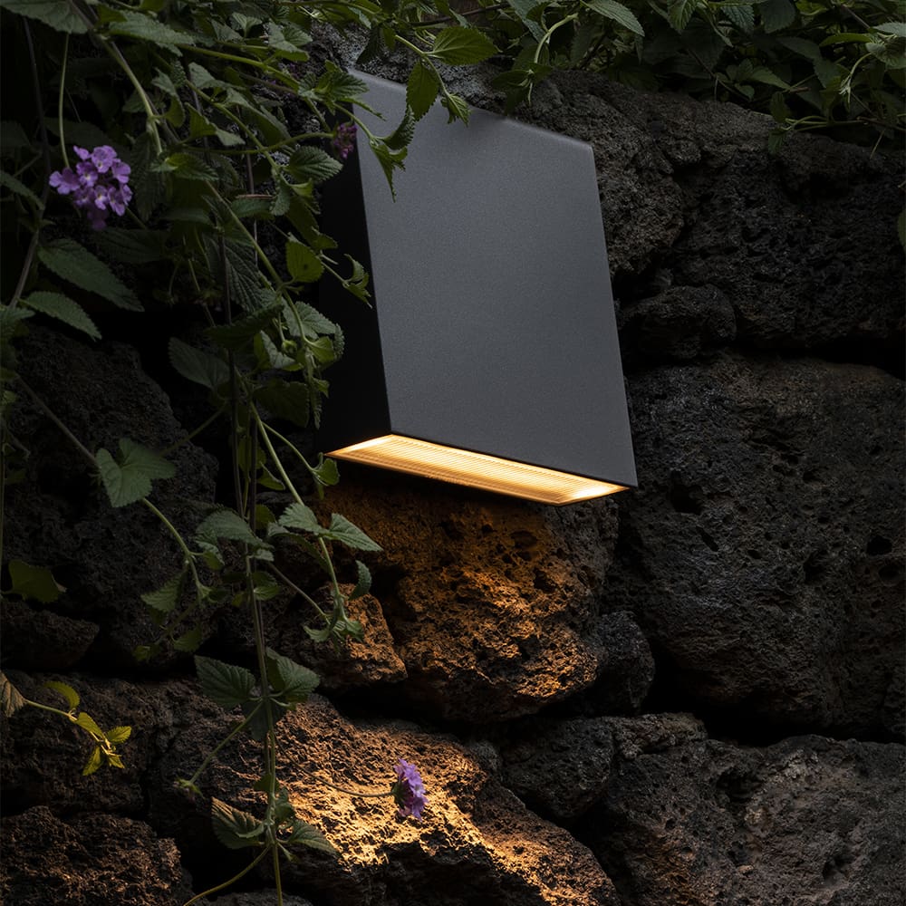 Artemide cuneo un applique per esterni su una paret di roccia illumina un giradino